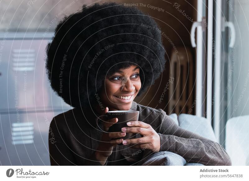 Cheerful black woman with cup of coffee hot drink beverage afro window smile leisure refreshment hairstyle feminine appearance happy charming brunette
