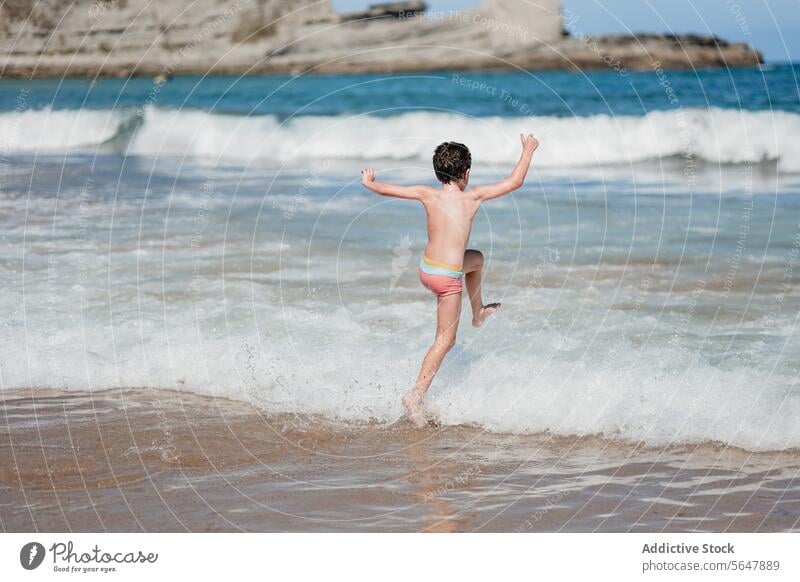 Joyful child playing in the ocean waves beach running sunny joyful fun water sea summer vacation holiday kid sand coastline frolic carefree outdoor activity