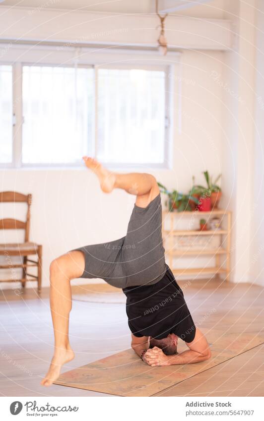 Flexible unrecognizable man practicing yoga in studio practice handstand flexible fit training perform sportswear balance room male upside down wellness asana