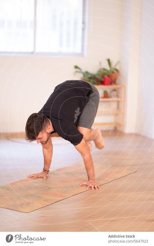 Young man practicing handstand in yoga studio practice balance training session activewear guy focused male wellness mat wellbeing window concentrate activity