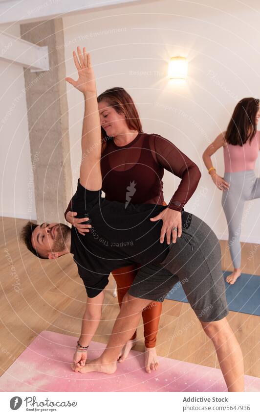Positive woman helping man with stretching exercises guy workout training colleague assist flexible mat wellbeing smile activity wellness healthy male practice