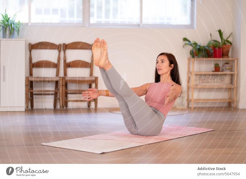 Focused lady stretching on mat during yoga practice woman sit sportswear training flexible focused wellness session studio female vitality mindfulness barefoot