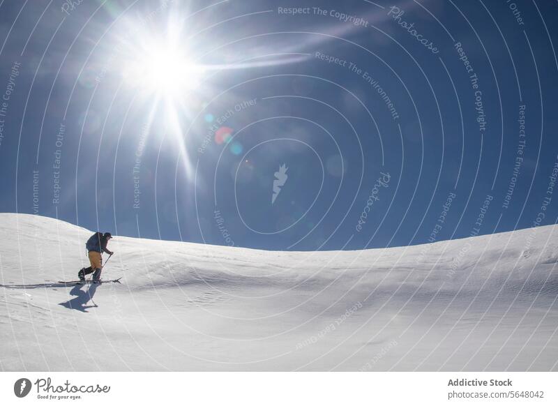 Man skiing on snowcapped mountain skier man anonymous backpack pole sport covering slope sun bright blue sky sunny canada active full body warm clothes