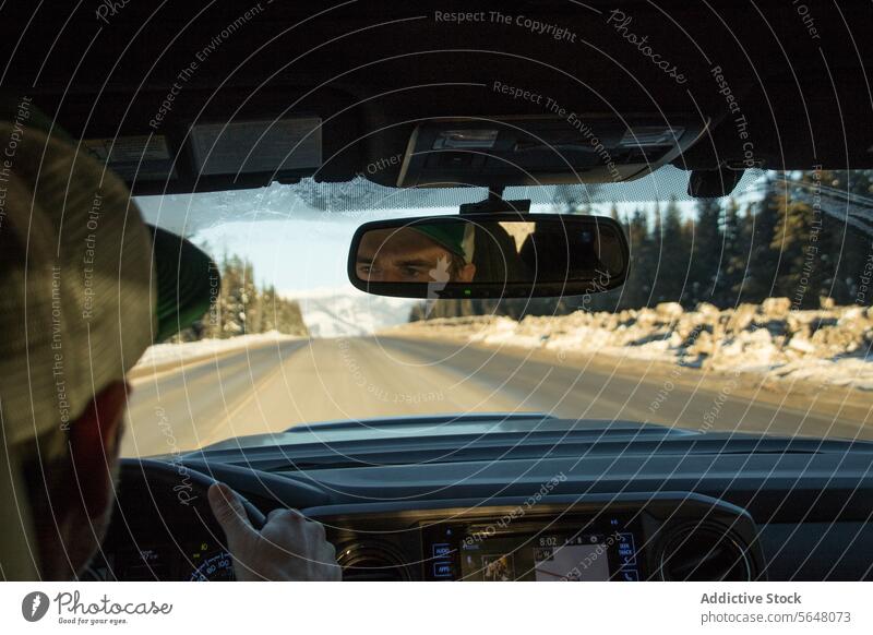 Man driving car during road trip traveler steering wheel man cap holding rearview mirror drive modern automobile countryside crop body part reflect glass