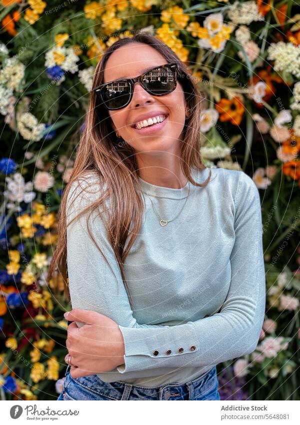 Woman smiling against a colorful flower background sunglasses woman smile flowers necklace cheerful vibrant floral beauty city street joy teeth expression style