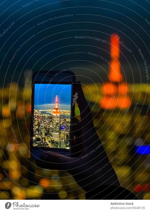 Tourist taking photo of glowing skyscrapers at night person tourist hand using smartphone take photo cityscape urban empire state building manhattan new york