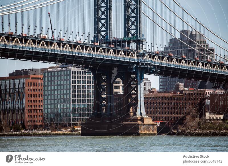 Manhattan Bridge's detailed architecture against city backdrop bridge New York East River steel cables towers water urban skyline buildings traffic