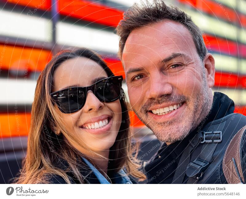 Joyful couple selfie with electronic flag in Manhattan New York display joy happiness city urban street man woman sunglasses laughter smile outdoors building