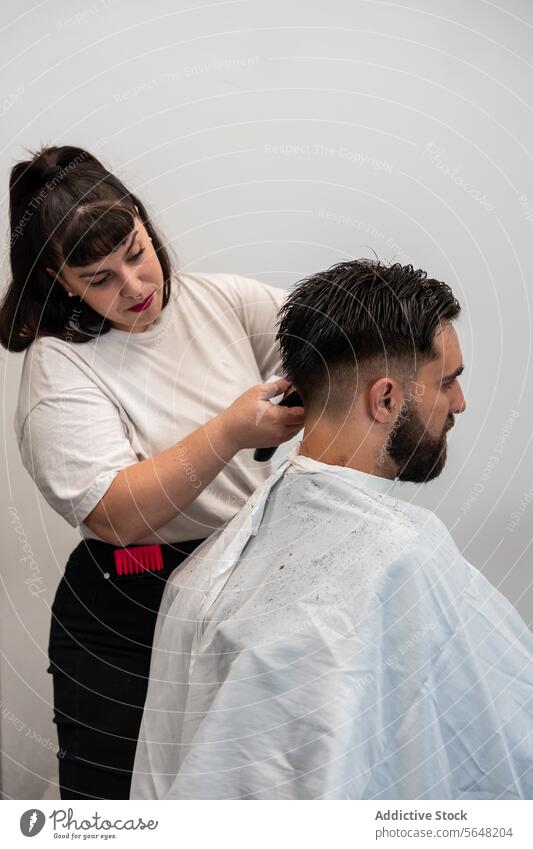Side view of focused female hairstylist using electric trimmer on male client's hair at salon Hairdresser Trimmer Man Salon Care Service Hand Client Process