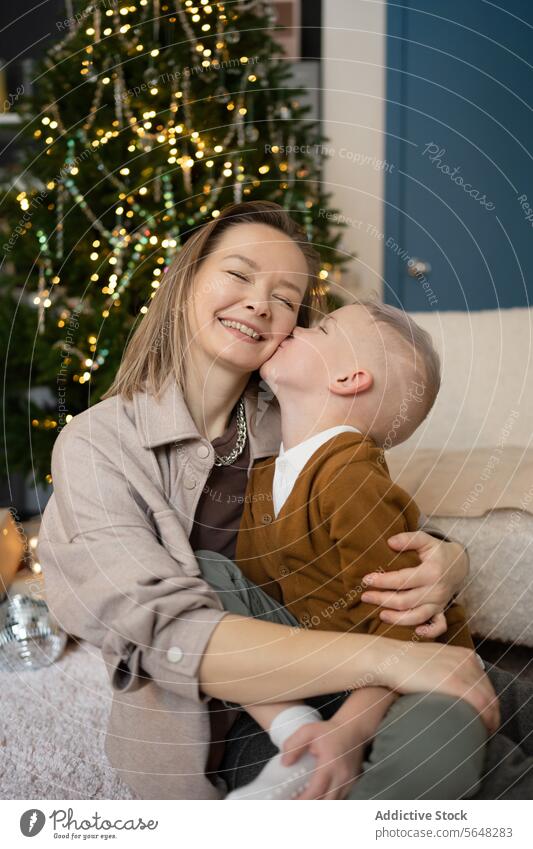 Mother and Son Sharing a Joyful Moment by the Christmas Tree mother son Christmas tree kiss smile festive holiday bond family warmth joy celebration affection