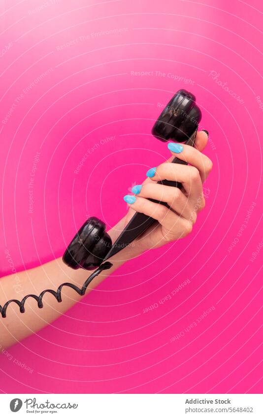 Hand of anonymous woman Holding Telephone Receiver hand holding telephone receiver black blue nail polish pink background vibrant communication call retro