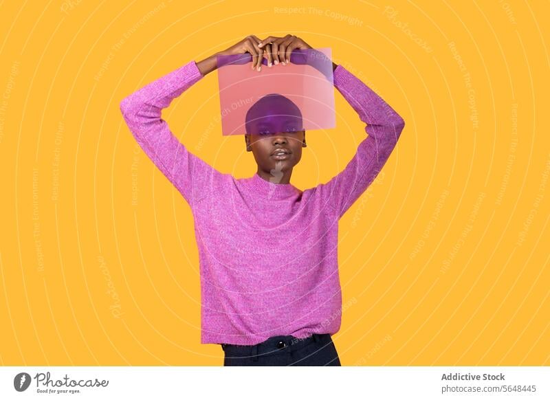 Black woman in warm clothing holding transparent plastic on yellow background purple sweater isolated african american copy space portrait advertisement