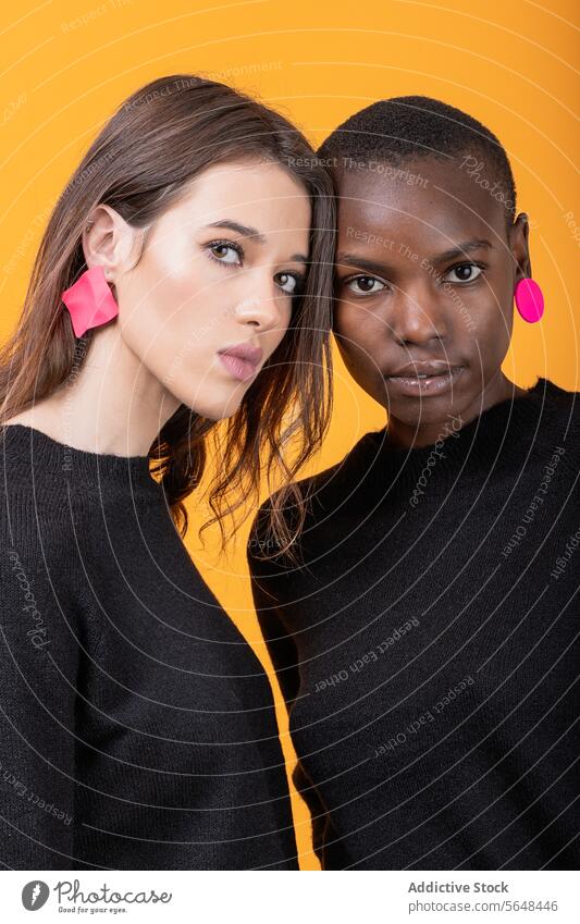 Diverse young female friends wearing pink earrings women diverse confident portrait trendy tshirt together multiracial casual attire posing pierced staring