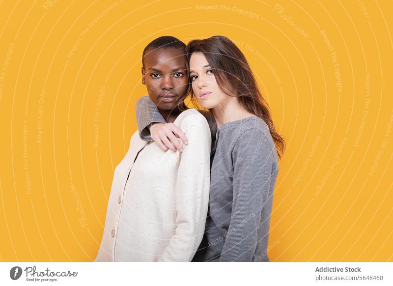 Diverse women in casuals isolated over yellow background looking at camera confident friend multiracial young trendy together casual attire posing staring