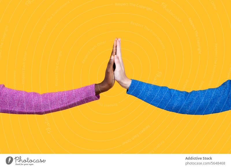 Anonymous multiracial women touching hands over yellow background diverse unity sweater together friend pink blue support crop collaborate community clasp