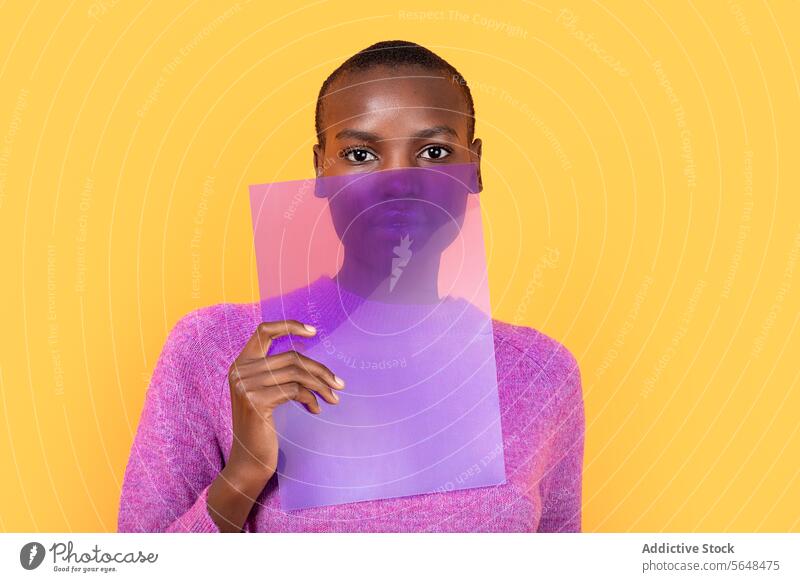 Black woman in warm clothing holding transparent plastic on yellow background purple sweater isolated african american copy space portrait advertisement