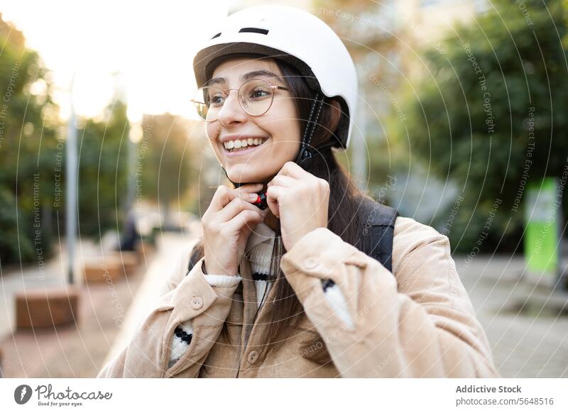 Smiling woman fastening helmet strap outdoors safety smiling ride cheerful young adult preparation secure white safety gear protection happy lifestyle transport