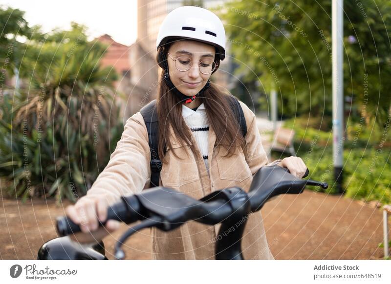 Young woman preparing to ride an electric scooter safety helmet casual wear transportation eco-friendly sunny day urban young female outdoor electronic vehicle