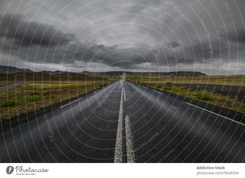 An open road stretches into the horizon under a brooding sky in a desolate Icelandic landscape stormy travel outdoor scenic highway journey adventure route
