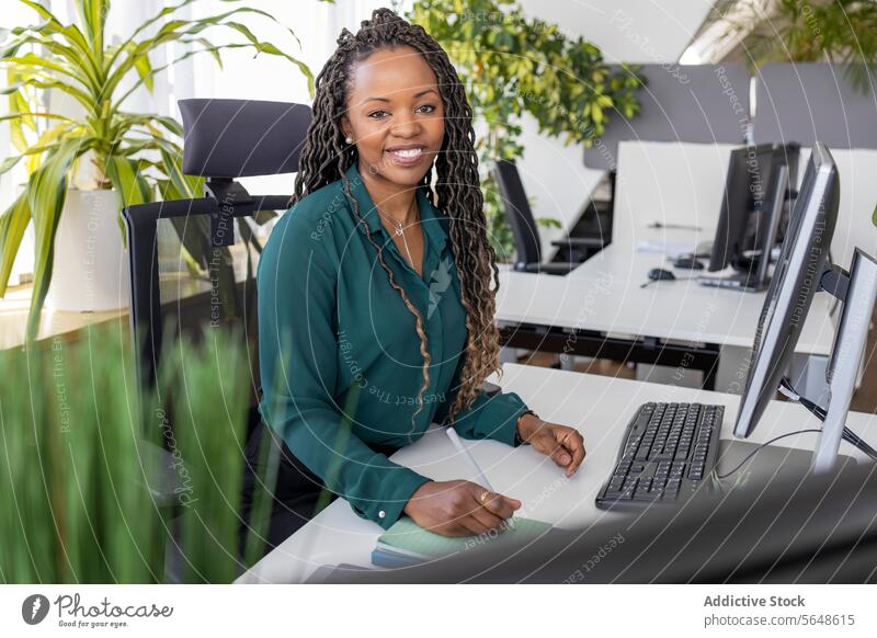 Happy businesswoman sitting at computer desk in office Businesswoman Portrait Computer Desk Office Confident Smile Monitor Eyeglasses Workplace Afro Copy Space