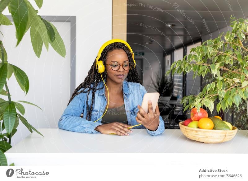 Businesswoman using headphones and smartphone in creative office Headphones Smartphone Using Office Music Smile Yellow Modern Creative Fruit Desk Work