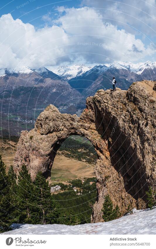 Hiker gazing at snowy peaks through a natural rock arch hiker natural arch rock formation pyrenees mountain nature adventure landscape torla ordesa stone scenic