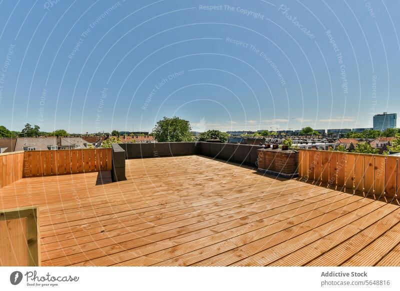 Wooden terrace against blue sky wooden empty neighborhood floorboard railing sunny suburb brown district sunlight property house building modern residential