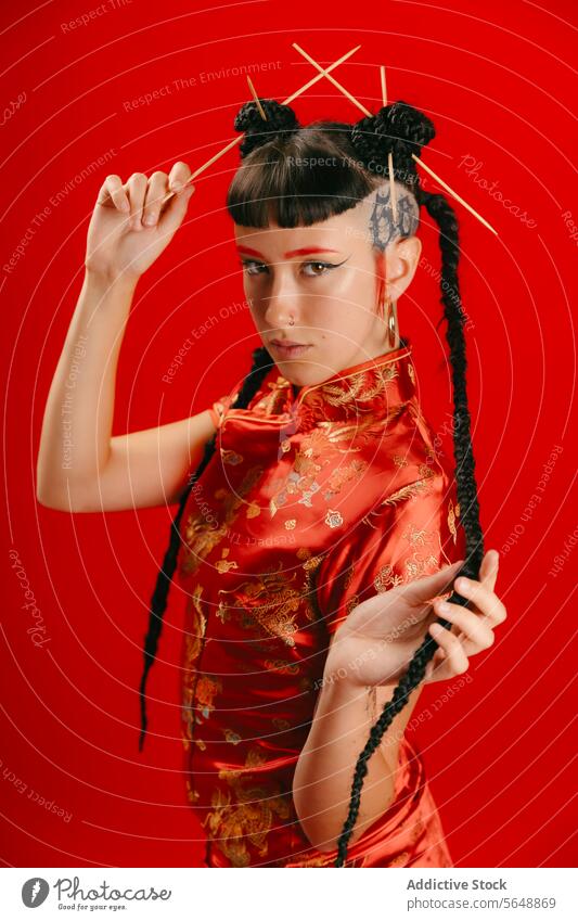 Stylish woman in traditional Asian attire on red background asian dress style hairstyle chopstick pose confident vibrant modern unique elegance beauty trend