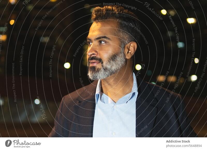 Portrait of well dressed bearded Indian businessman in street portrait indian man elegant stand lamps looking away clothes evening illuminate formal glow male