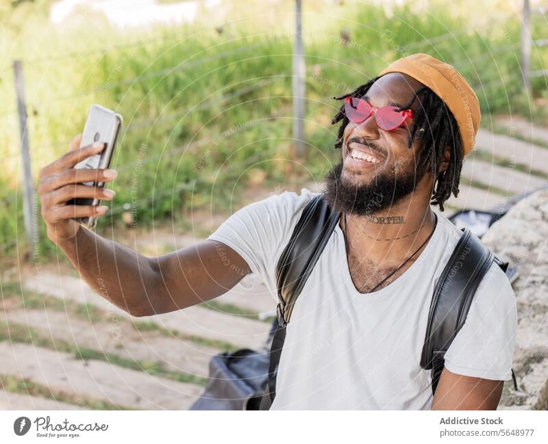 Cheerful male hipster taking selfie in park man using smartphone social media summer memory moment smile cool cheerful young black ethnic african american