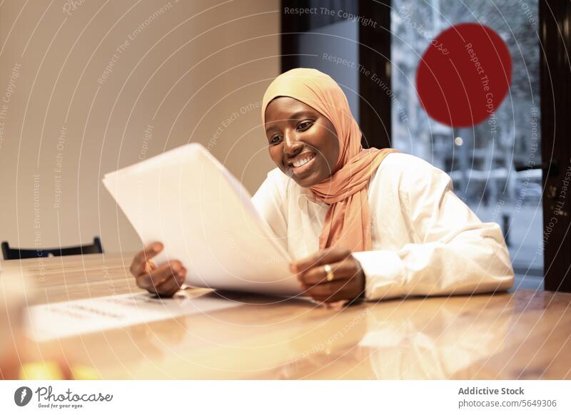 Happy Islamic woman reading paper documents paperwork smile hijab headscarf project office entrepreneur occupation table modern business manager professional