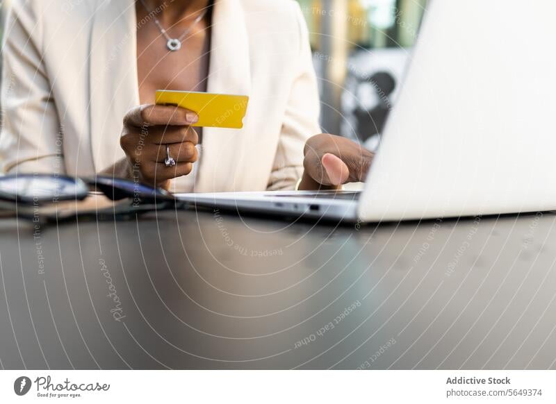 Unrecognizable crop black businesswoman doing online shopping at cafe executive credit card laptop payment table manager convenience entrepreneur professional