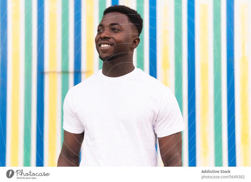 Cheerful black man against striped wall city street urban colorful geometry pattern daytime toothy smile cheerful happy positive afro male young