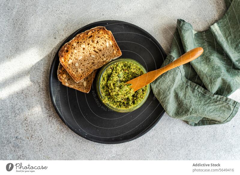 Delicious rye bread served with pesto spread with spoon and napkin sauce plate tasty homemade delicious bowl cutlery table food cuisine appetizing gourmet baked