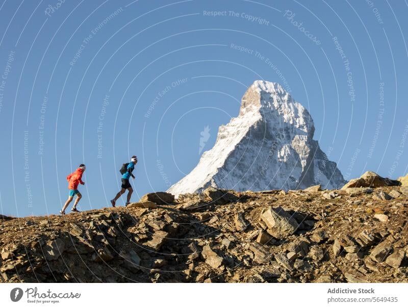 Hikers Near in colorful attire traversing Matterhorn hikers trail rocky snow-covered mountain clear sky outdoor activity trekking adventure travel landscape