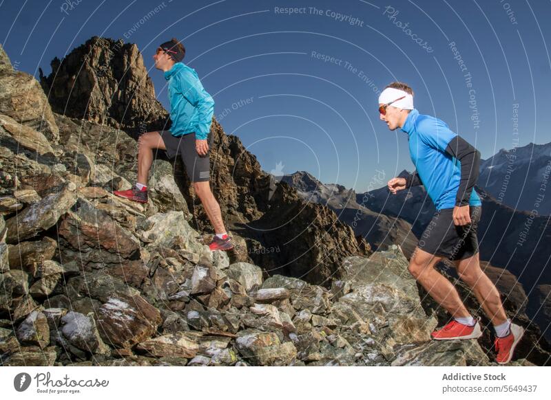 Runners trail Running with Matterhorn View runner athletic wear jogging steep rocky incline snow-covered mountain distance outdoor sport running fitness