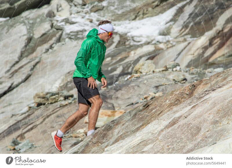 Focused trail runner ascending a rocky slope mountain sportswear running ascent outdoor fitness exercise athlete training endurance nature adventure landscape