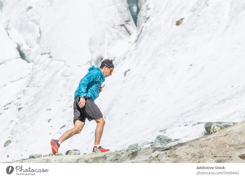 Concentrated trail runner ascending a rocky slope mountain sportswear running ascent outdoor fitness exercise athlete training endurance nature adventure