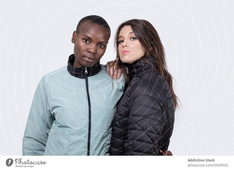 Confident diverse female friends in jackets over white background Women Portrait Jacket Winter Hand On Chin Multiracial Stand Together Girlfriend Love Young