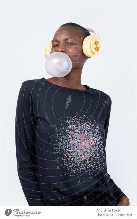Contented black woman witj eyes closed listening music while blowing bubble gum Woman Headphones Music Bubble Gum Blow Fashion Enjoy Model Eyes Closed Happy