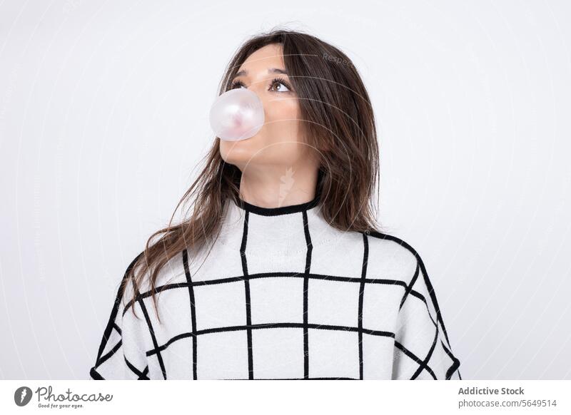 Thoughtful young woman blowing bubble gum against white background Woman Blow Bubble Gum Model Looking Away Sweater White Cool Pretty Young Isolated Fashion