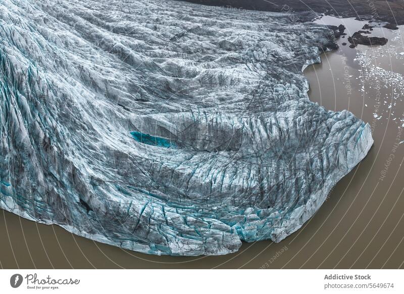 From above aerial shot showcasing a glacier coursing through Vatnajokull National Park in Iceland, surrounded by rugged terrain aerial view