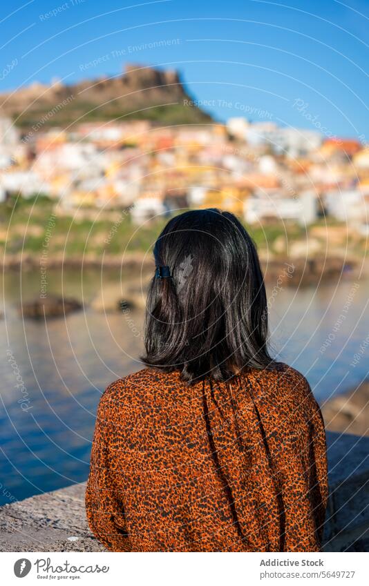 Woman admiring town and sea in vacation tourist castelsardo shore blue sky sunny back view anonymous casual attire looking woman explore travel lifestyle