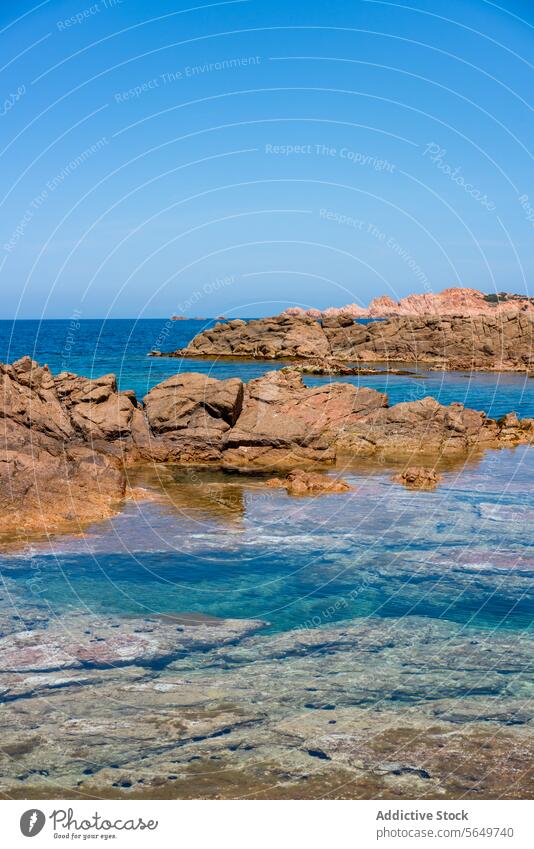 Rocky beach and blue sea under clear sky ocean rock formation water seashore scenic idyllic serene sunny rough brown calm nature tranquil scenery horizon