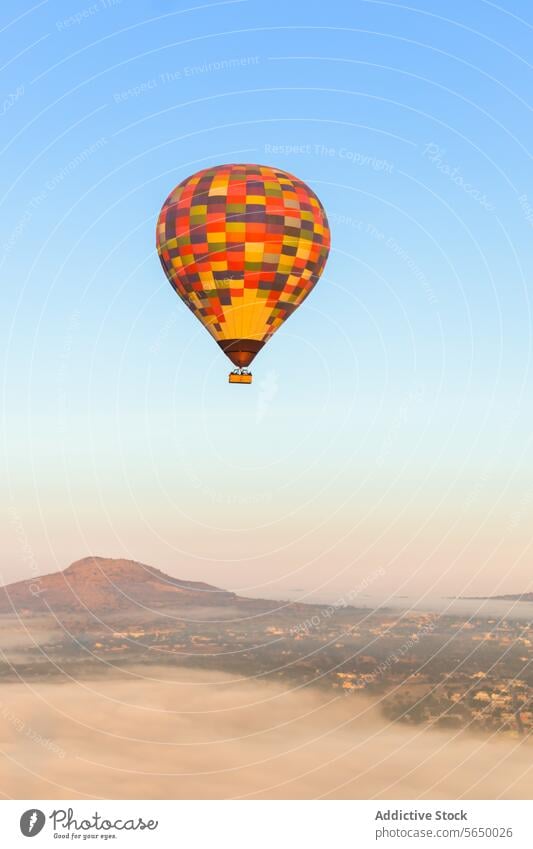 Hot air balloon floats in sky mist-covered landscape hot air balloon Mexico flight Teotihuacan outdoor adventure transport golden hour romance nature solitude