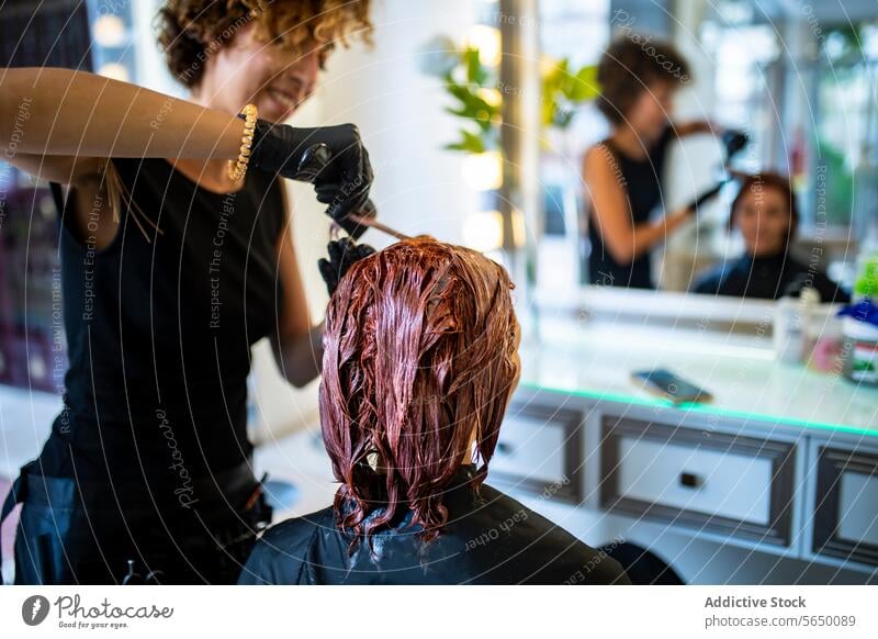 Hair coloring process in a modern salon hair stylist dye application client hairdresser mirror reflection work progress hair care treatment beauty fashion style