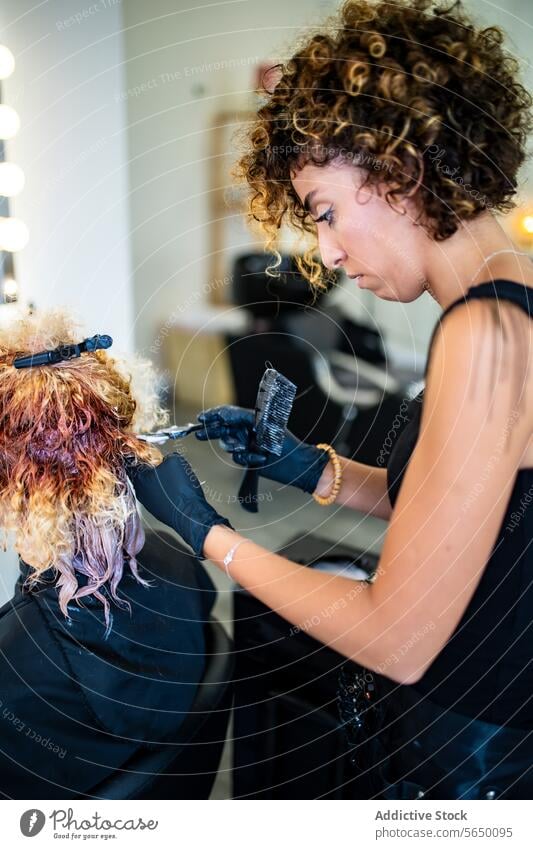 Hairstylist applying color to client's hair in salon hairstylist coloring dye application curly professionalism beauty treatment haircare dyeing styling fashion