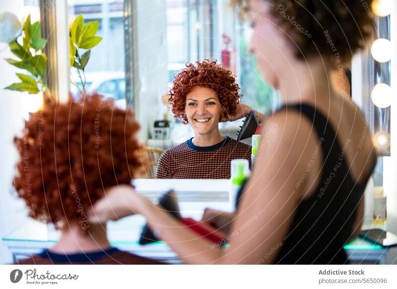 Smiling woman styling her curly hair in salon mirror hair styling hair straightener smile hair salon cheerful modern reflection red hair beauty hairstyle