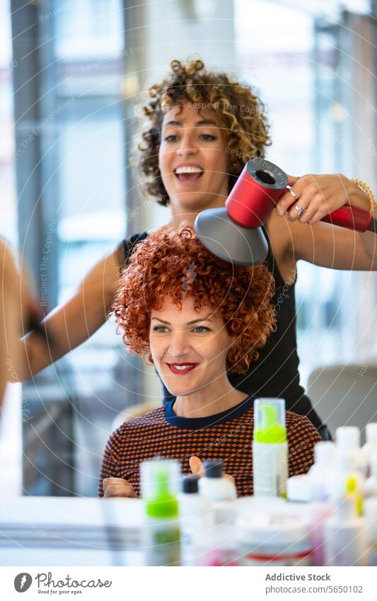 Stylist blow drying a client's curly hair at the salon stylist hair salon woman red hair blow dryer professional hairdresser beauty hairstyle modern smiling