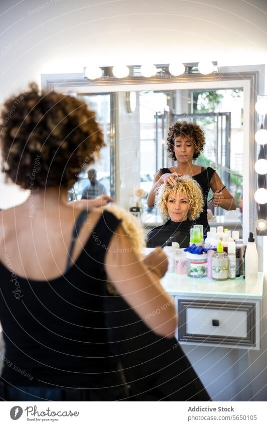 Hairstylist shaping a client's curls at the salon hairstylist mirror beauty product professional seat beauty salon hairdressing care style fashion coiffure